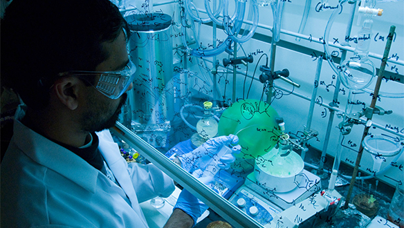 Scientist works with lab equipment under hood.